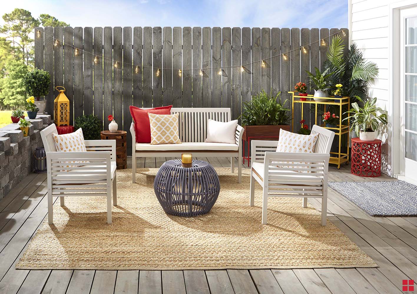 A light beige bench and two chairs on a wooden deck. 