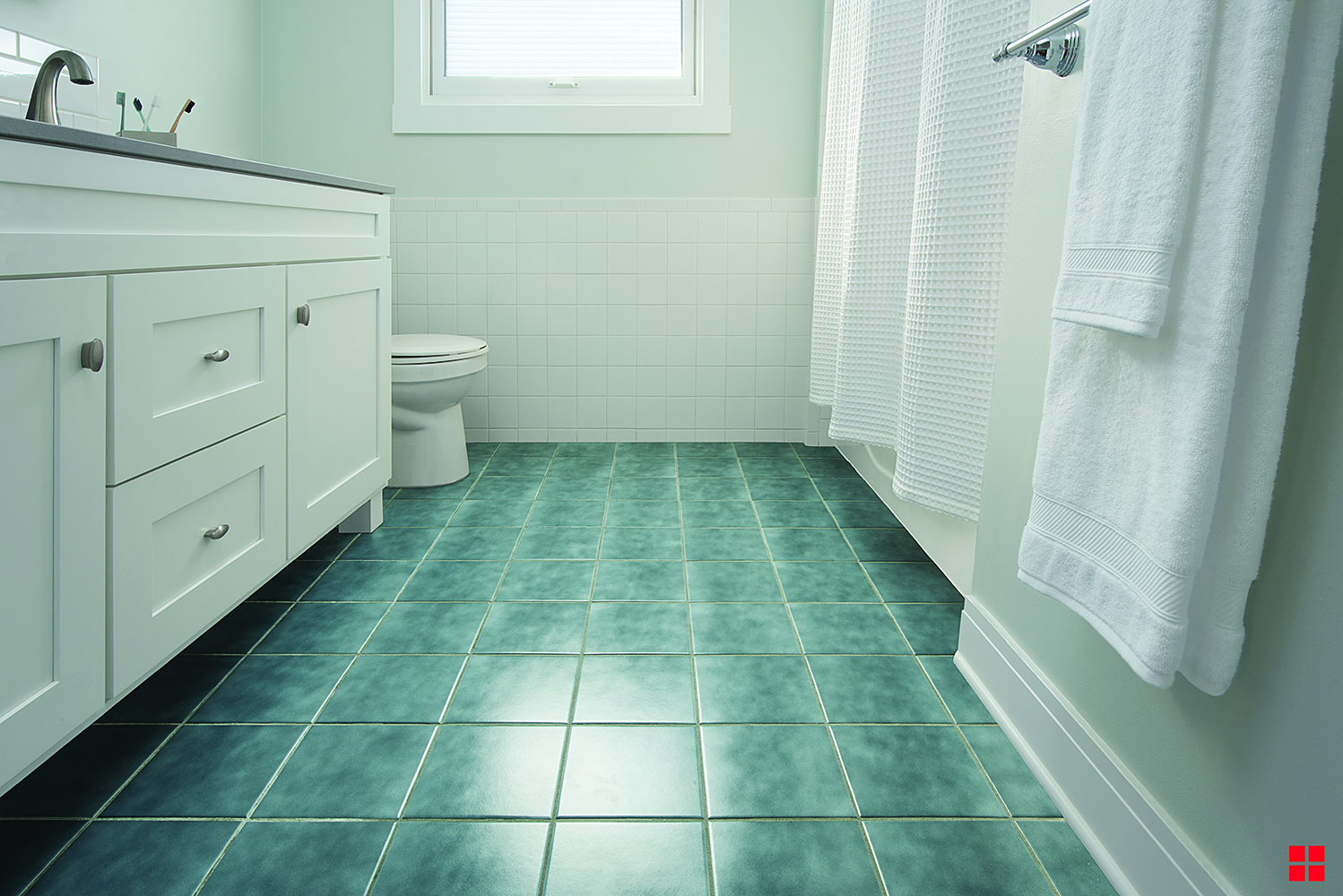 Bathroom with a white vanity and a blue tile floor with white grout. 