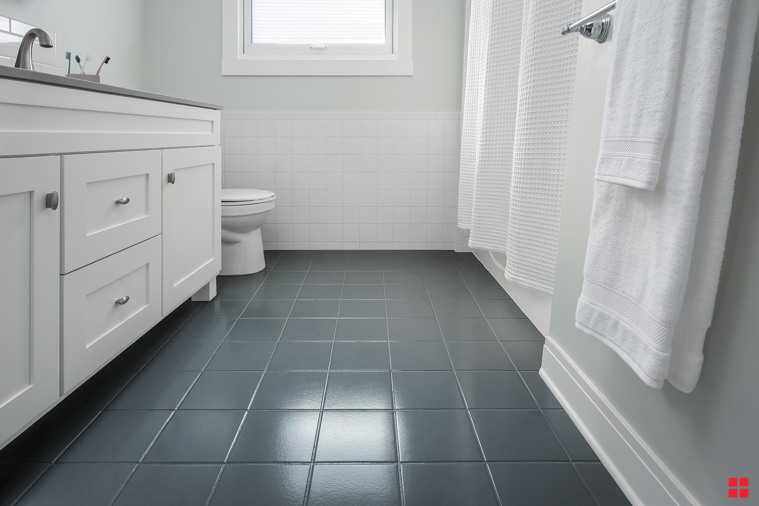 Bathroom with a white vanity and dark gray tile floor and grout. 